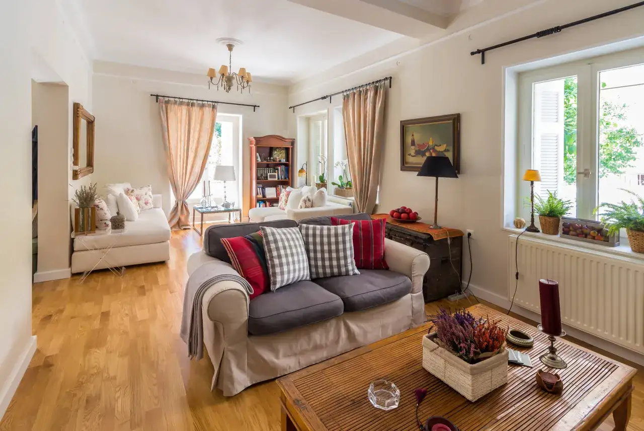 Przytulny salon w stylu angielskim z wygodnymi sofami, drewnianymi meblami i ciepłymi zasłonami.