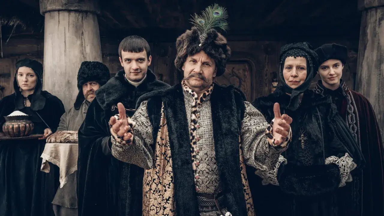 Gang zielonej rękawiczki w historycznych strojach, z pawim pi&oacute;rem na czapce wodza.