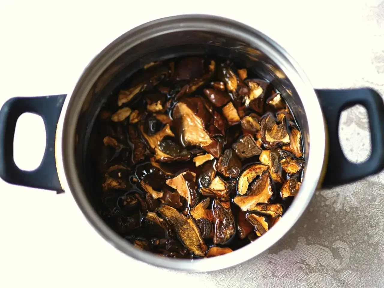 Suszone grzyby w garnku, gotowe do dalszej obróbki. Dowiedz się, jak długo gotować suszone grzyby, by wydobyć ich pełnię smaku.