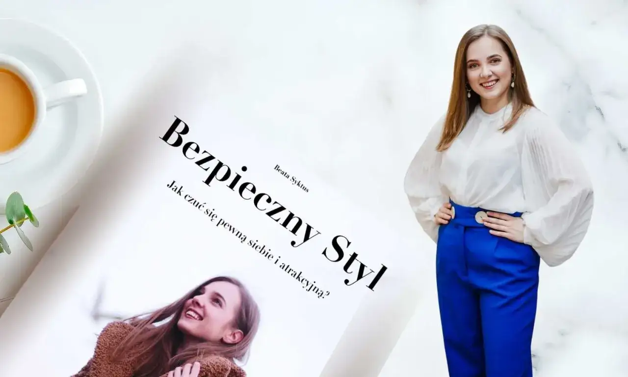 Kobieta w białej bluzce i niebieskich spodniach pozuje obok książki 