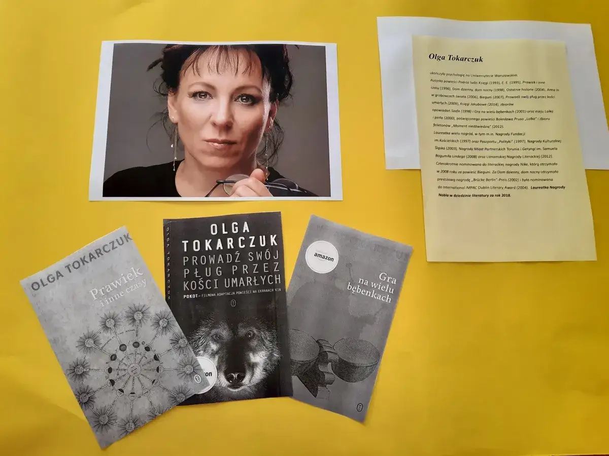 Olga Tokarczuk, laureatka Nagrody Nobla, na tle swoich książek i portretu.