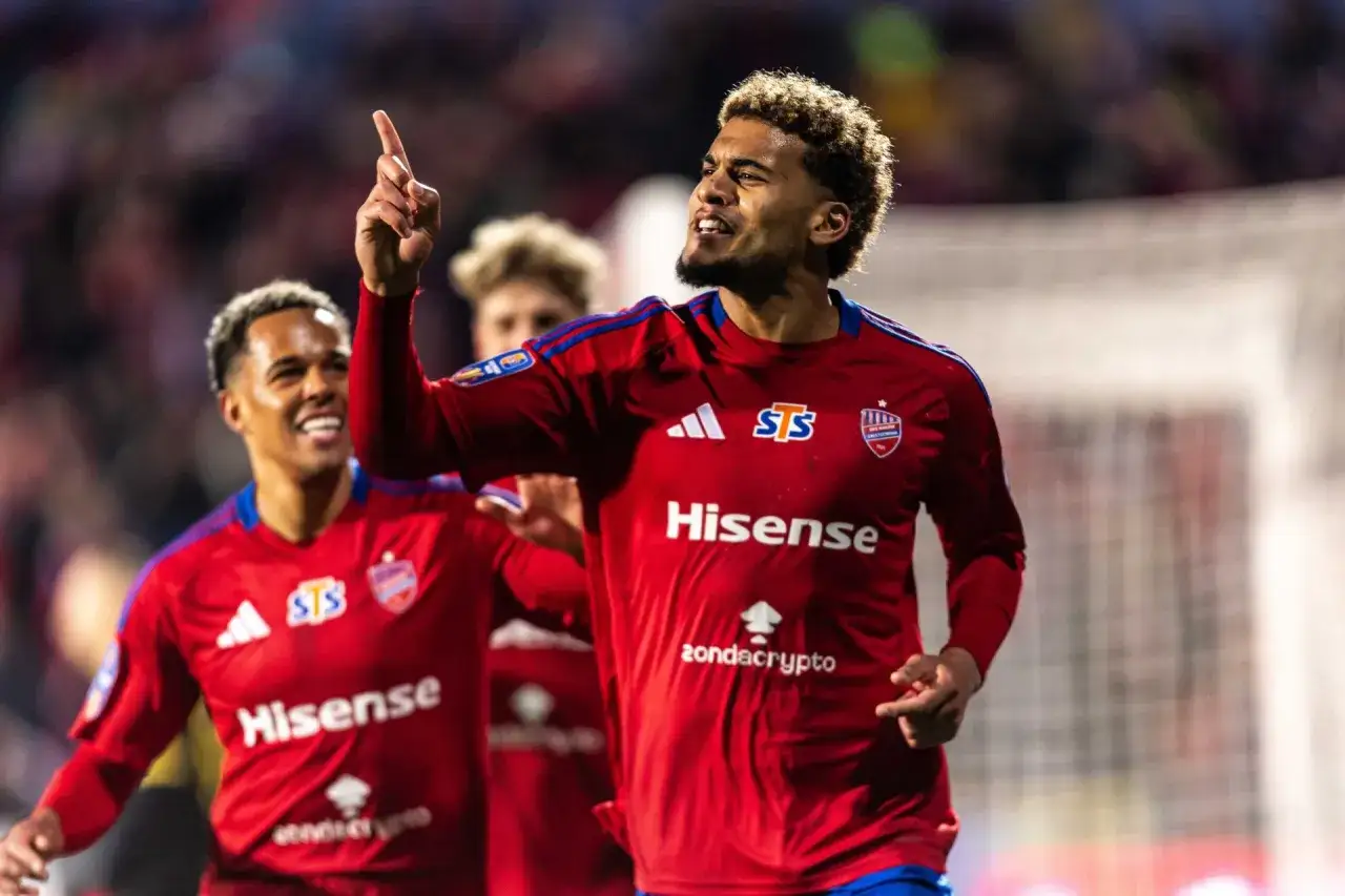 Piłkarz w czerwonej koszulce z numerem 5 świętuje bramkę, kiedy gra ekstraklasa.