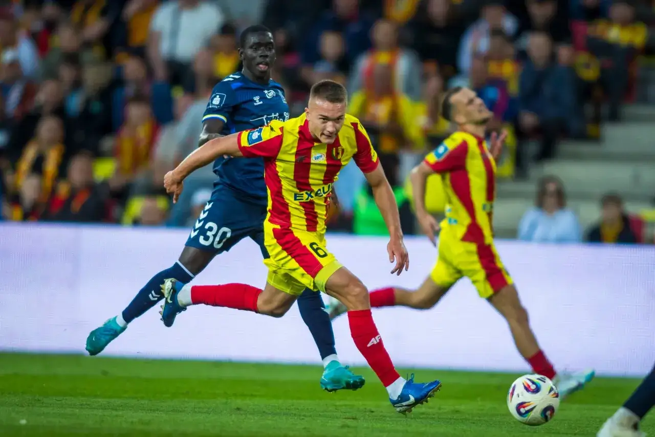 Piłkarze w żółto-czerwonych strojach walczą o piłkę. Kto pokaże ekstraklasę w tym meczu?