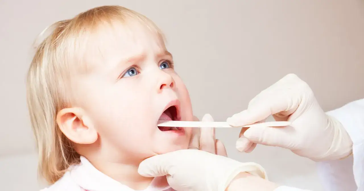 Lekarz bada gardło dziecka, szukając odpowiedzi na pytanie: co na chrypę u dziecka.