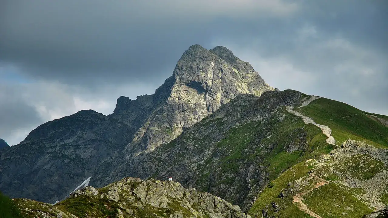 Kamienisty szlak pnie się po zielonym zboczu w kierunku skalistego szczytu. Czy szlak na Świnicę jest otwarty?