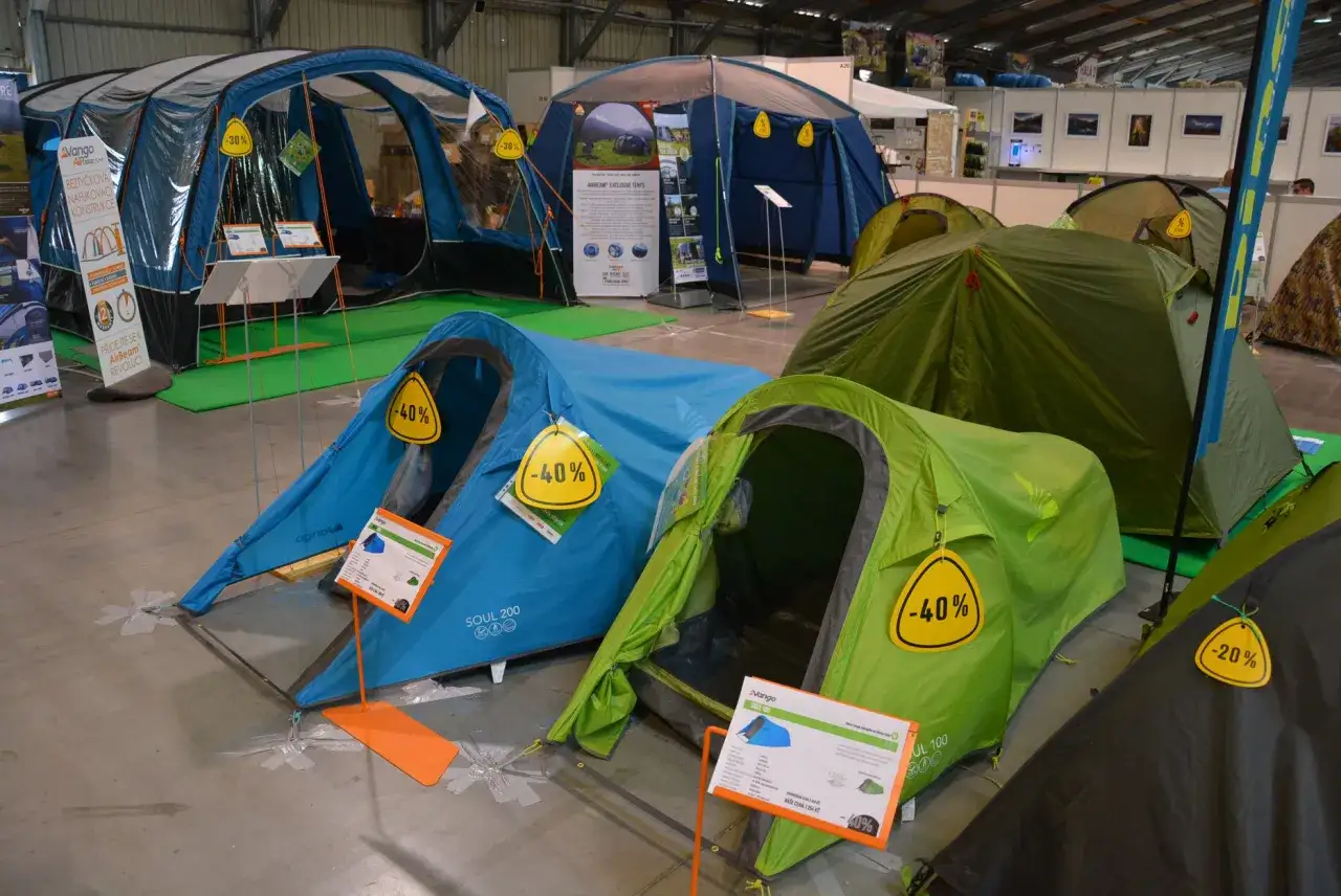 Wyb&oacute;r namiotu na kemping: niebieskie, zielone i czarne namioty na wystawie, niekt&oacute;re z rabatem -40%.
