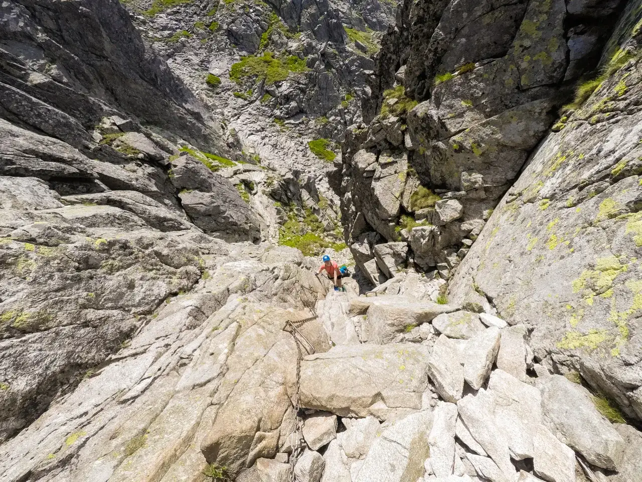 Wspinaczka na Kozi Wierch. Trasa skalista z łańcuchami, turystka w kasku pokonuje trudny odcinek.
