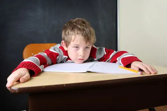 dziecko w szkolnej ławce potrzebujące pomocy