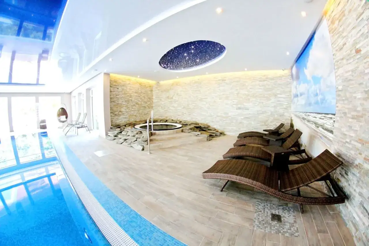 Relaks w hotelu Tristan Kąty Rybackie: basen, jacuzzi otoczone kamieniami, leżaki i sufit z gwiazdami.