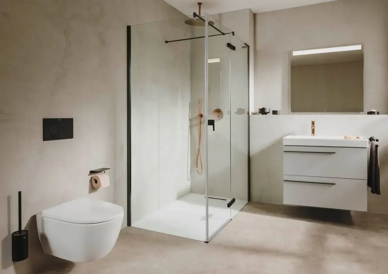 Nowoczesna łazienka z prysznicem walk-in i podwieszaną toaletą. Ściany i podłoga pokryte są eleganckim mikrocementem w neutralnym kolorze.
