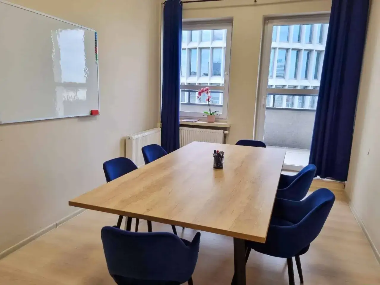 Sala do nauki angielskiego dla dorosłych. Duży st&oacute;ł, wygodne krzesła i tablica czekają na uczestnik&oacute;w wakacyjnego kursu angielskiego.