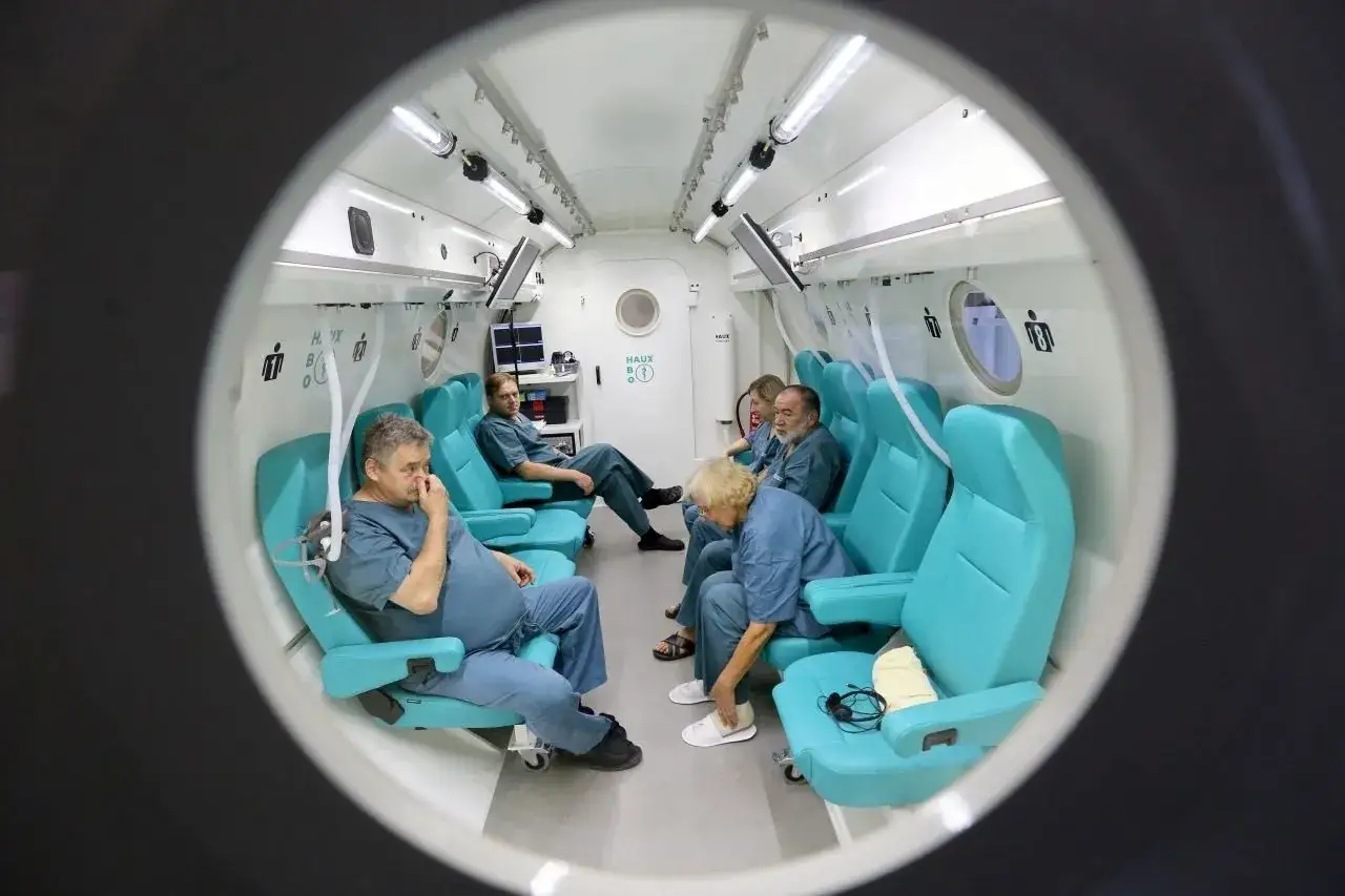 Ludzie w komorze hiperbarycznej, przygotowujący się do terapii tlenowej. Tak działa komora dekompresyjna, zwiększając ciśnienie.