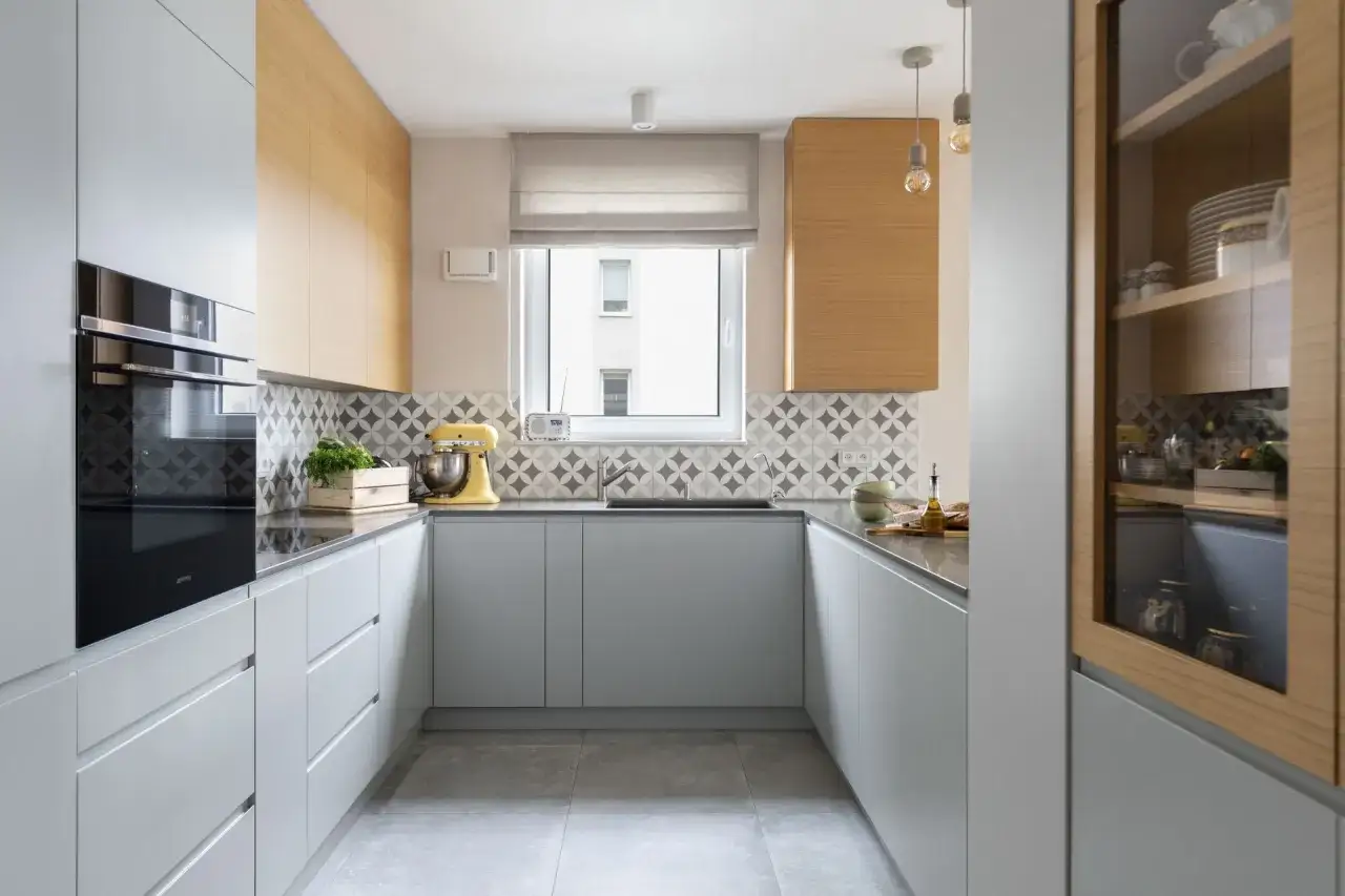 Nowoczesna kuchnia z szarymi frontami, drewnianymi panelami i geometryczną żywicą na ścianie w kuchni nad blatem.