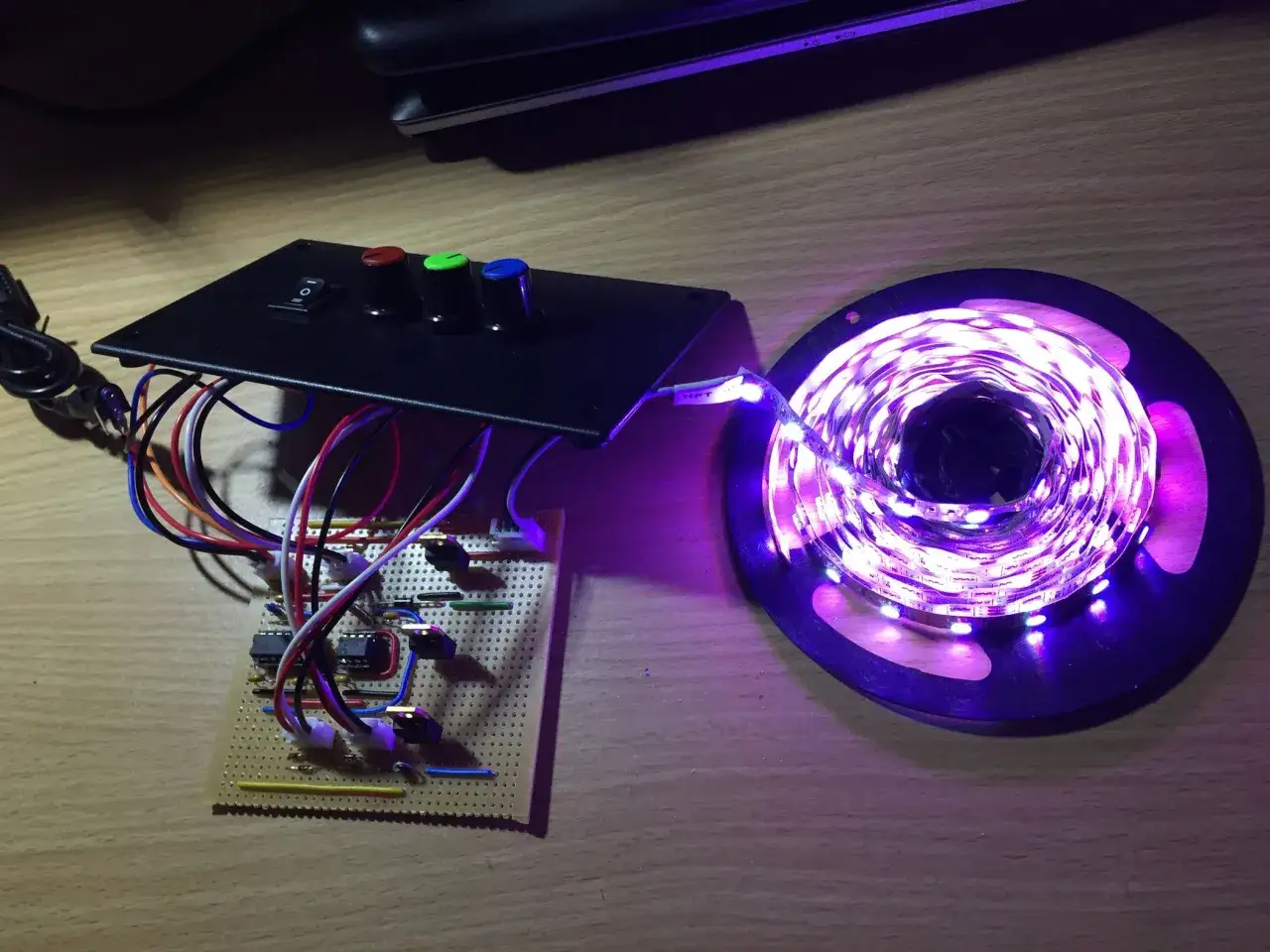 DIY sterownik LED RGB schemat z potencjometrami i przełącznikiem, podłączony do taśmy LED świecącej na fioletowo.