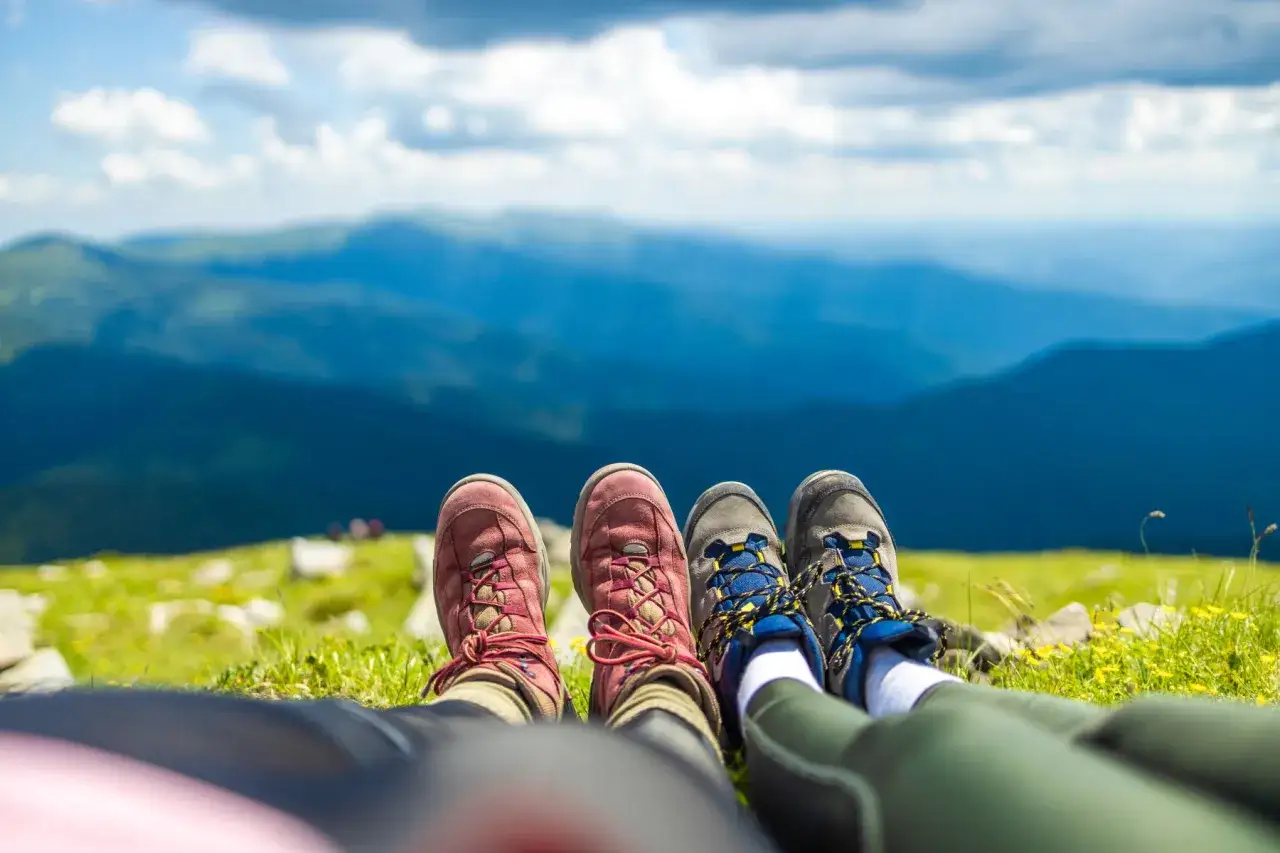 Stopy w butach trekkingowych na tle gór. Idealny widok, by zacząć chodzić po górach.