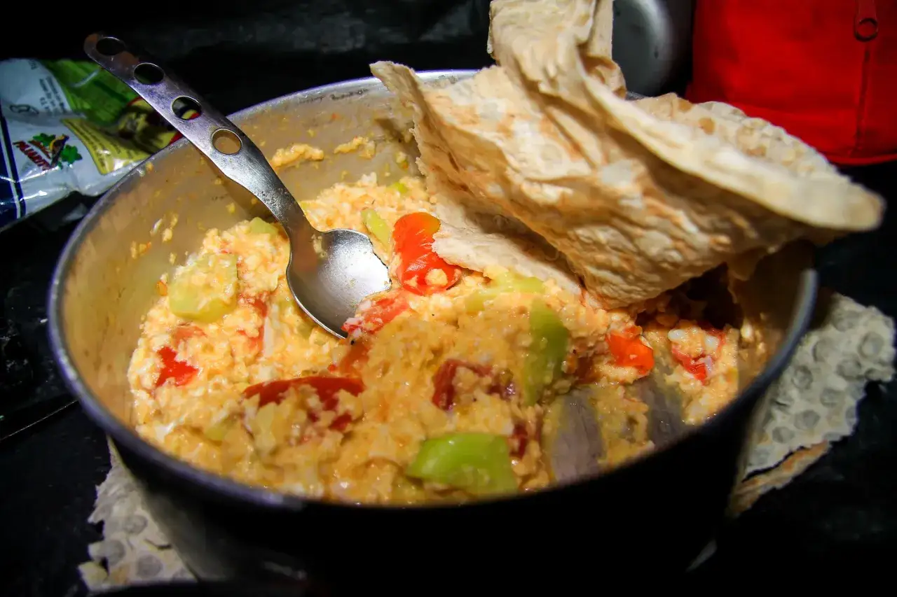 Pyszne jedzenie na biwak: jajecznica z pomidorami i papryką, podana z chlebem.