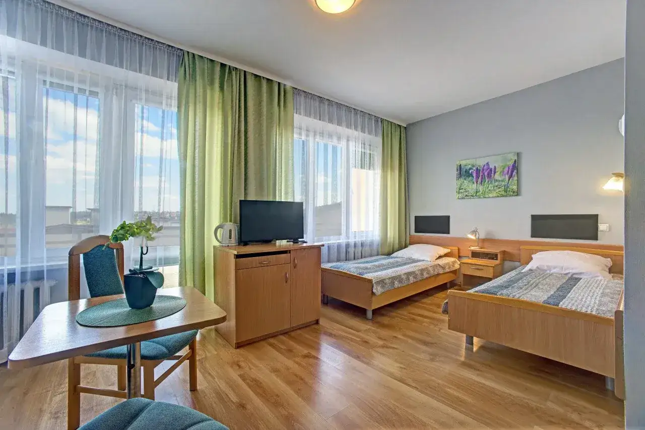 Pokój w górniczym sanatorium. Dwa łóżka, stolik, telewizor. Idealne miejsce dla każdego górnika na odpoczynek.