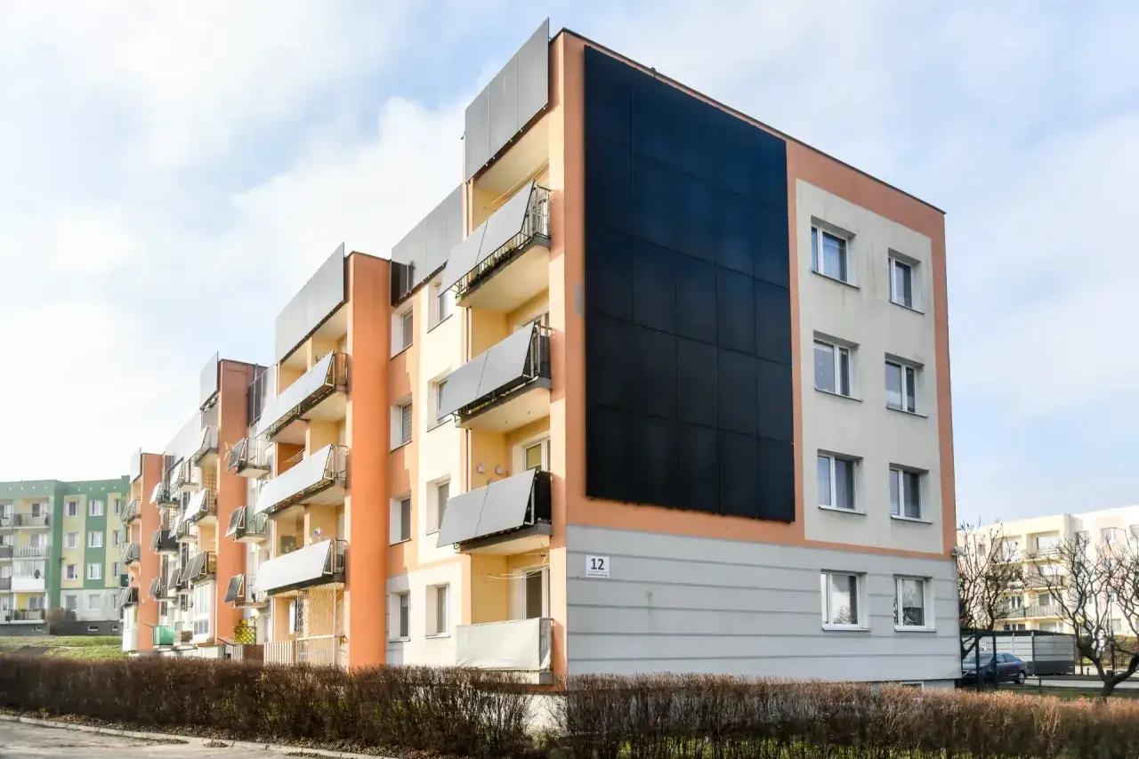 Nowoczesny blok mieszkalny z panelami fotowoltaika na elewacji.