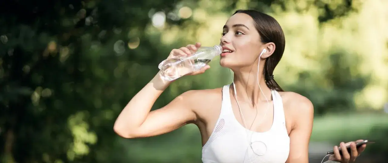 Osoba pijąca wodę i ubrana odpowiednio do pogody