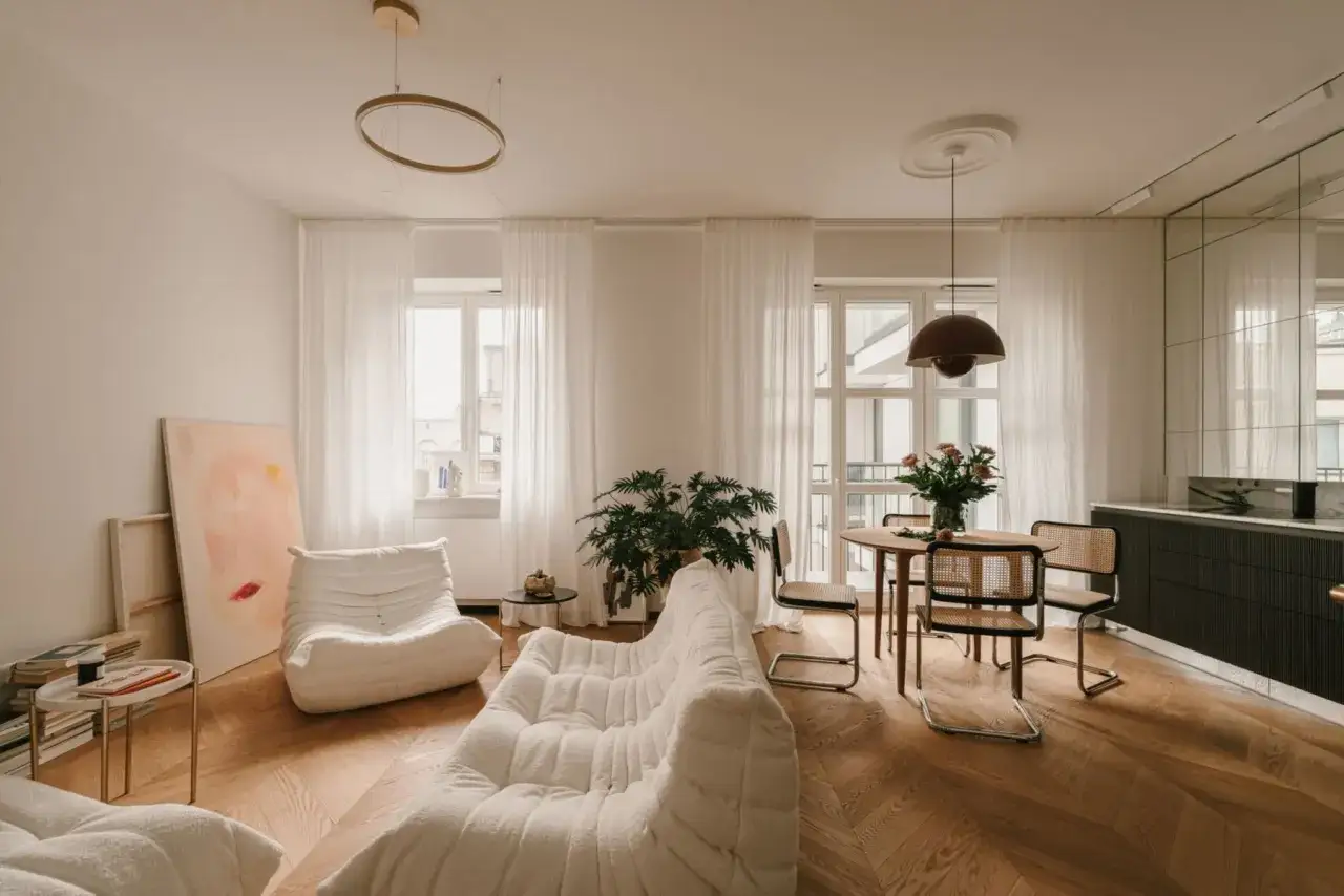 Przytulny salon w kolorze ecru z wygodnymi sofami, okrągłym stolikiem i jadalnią.