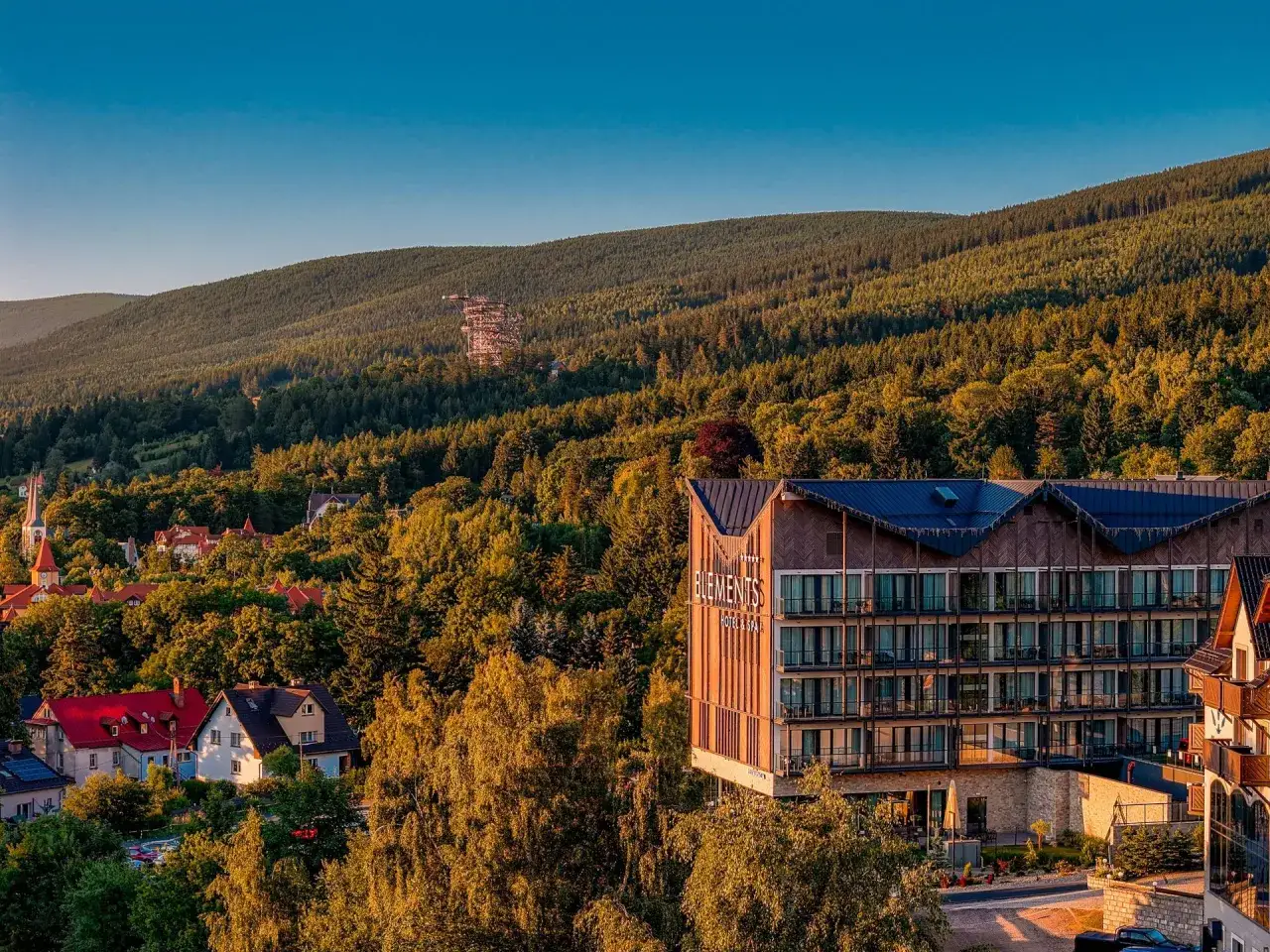 Hotel Spa Bieszczady w otoczeniu zielonych wzgórz, z widokiem na las i okoliczne domy.
