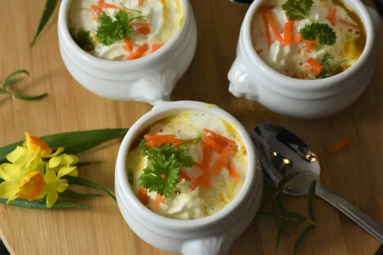 Pyszne, kremowe danie, idealne jako co na obiad dla dzieci. W małych białych miseczkach, udekorowane marchewką i natką pietruszki.