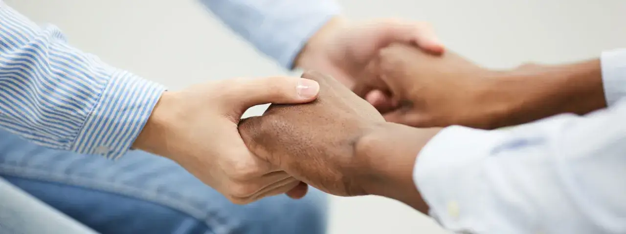 Dwie dłonie, jasna i ciemna, splatają się w geście pojednania. To przeprosiny prosto z serca, symbol zrozumienia i nadziei na lepsze jutro.