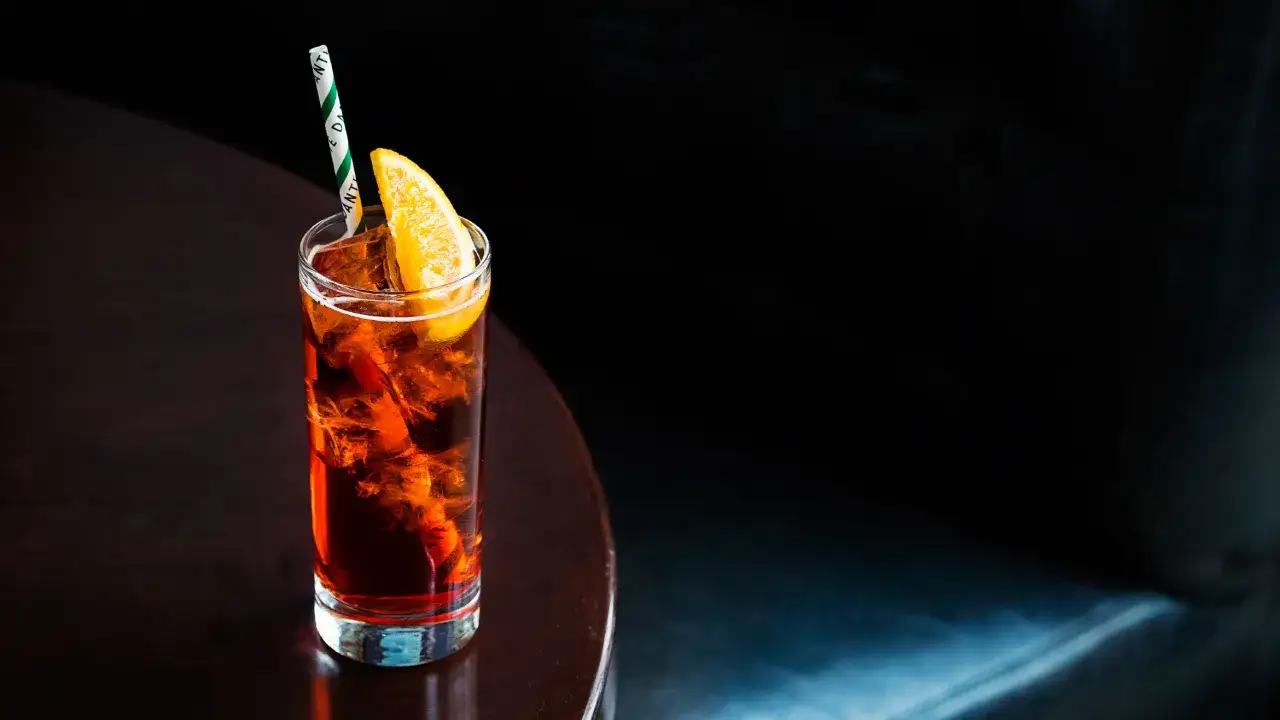 Orzeźwiający drink z lodem, plasterkiem pomarańczy i słomką. Czy to Campari czy Aperol?
