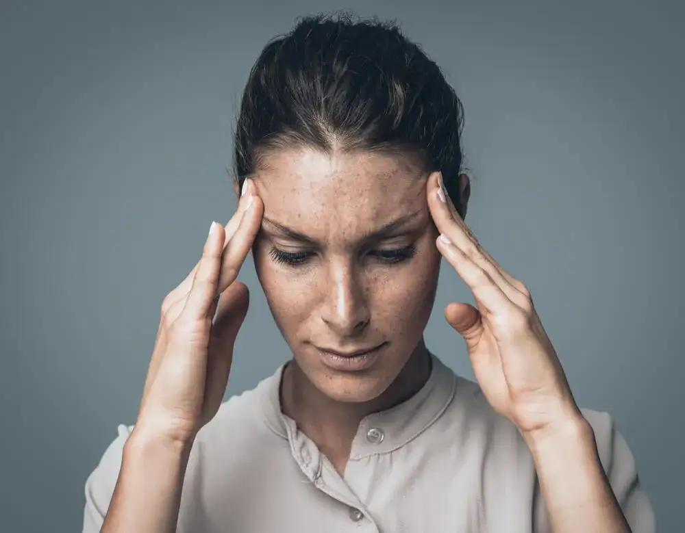 Osoba z b&oacute;lem głowy, trzymająca się za skronie