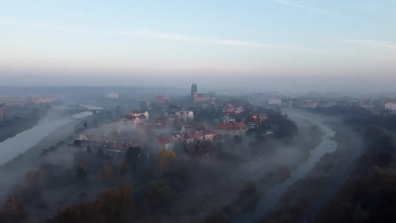 Mglisty poranek nad rzeką, wyłaniające się z mgły kamienice i katedra. Poznań atrakcje w jesiennej odsłonie.