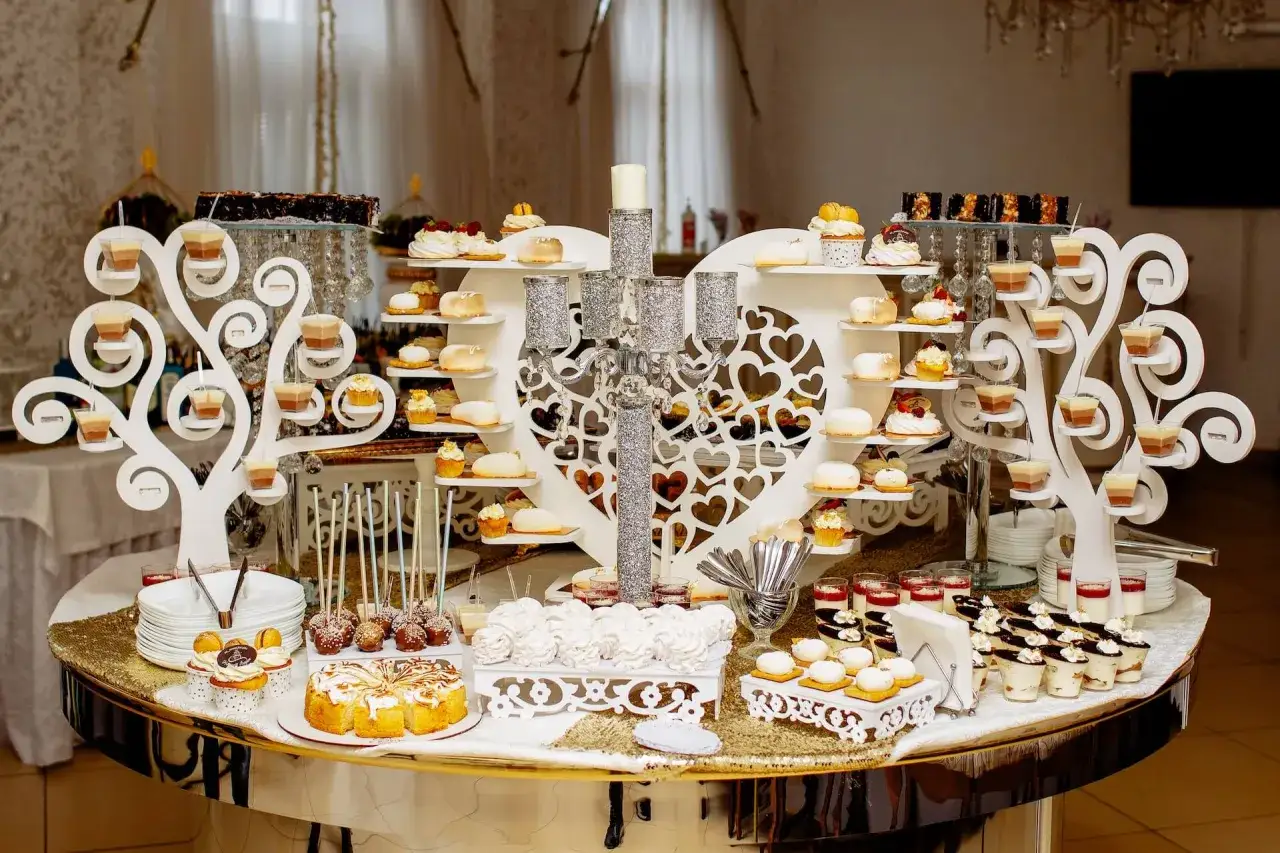 Słodki stół na komunię jak zrobić: bogactwo deserów, babeczek i musów na białych drzewkach i sercu.