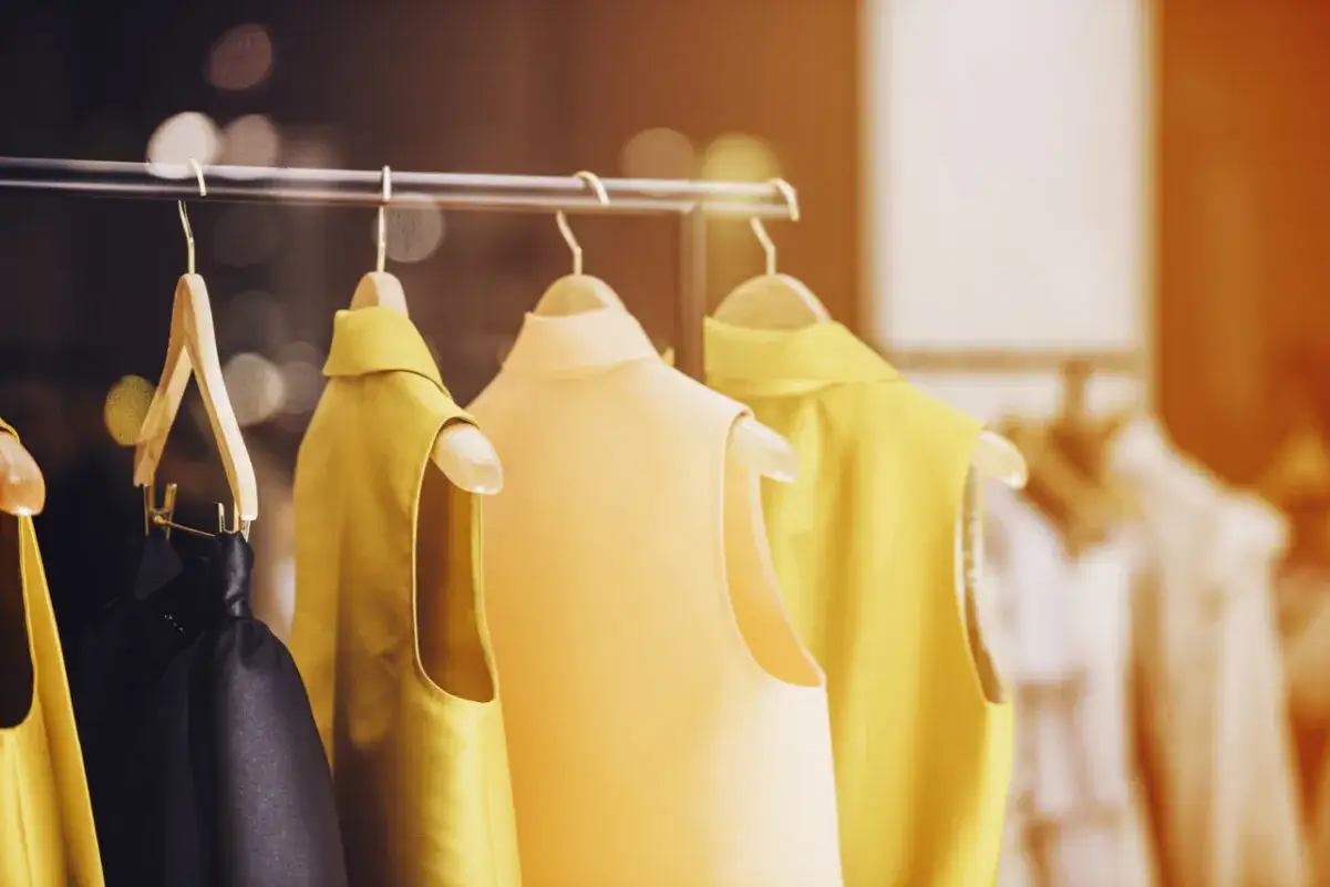 Eleganckie, używane ubrania na wieszakach. Czy warto wejść w handel produktami używanymi? Model recommerce to przyszłość mody.