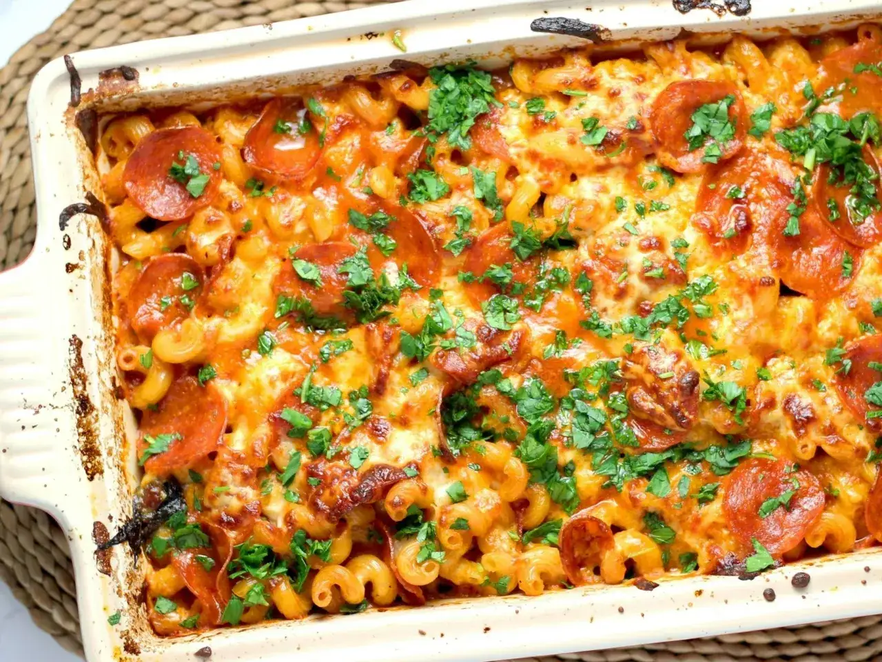 Pyszne spaghetti z piekarnika z serem i pepperoni, posypane świeżą natką pietruszki. Idealne na rodzinny obiad.