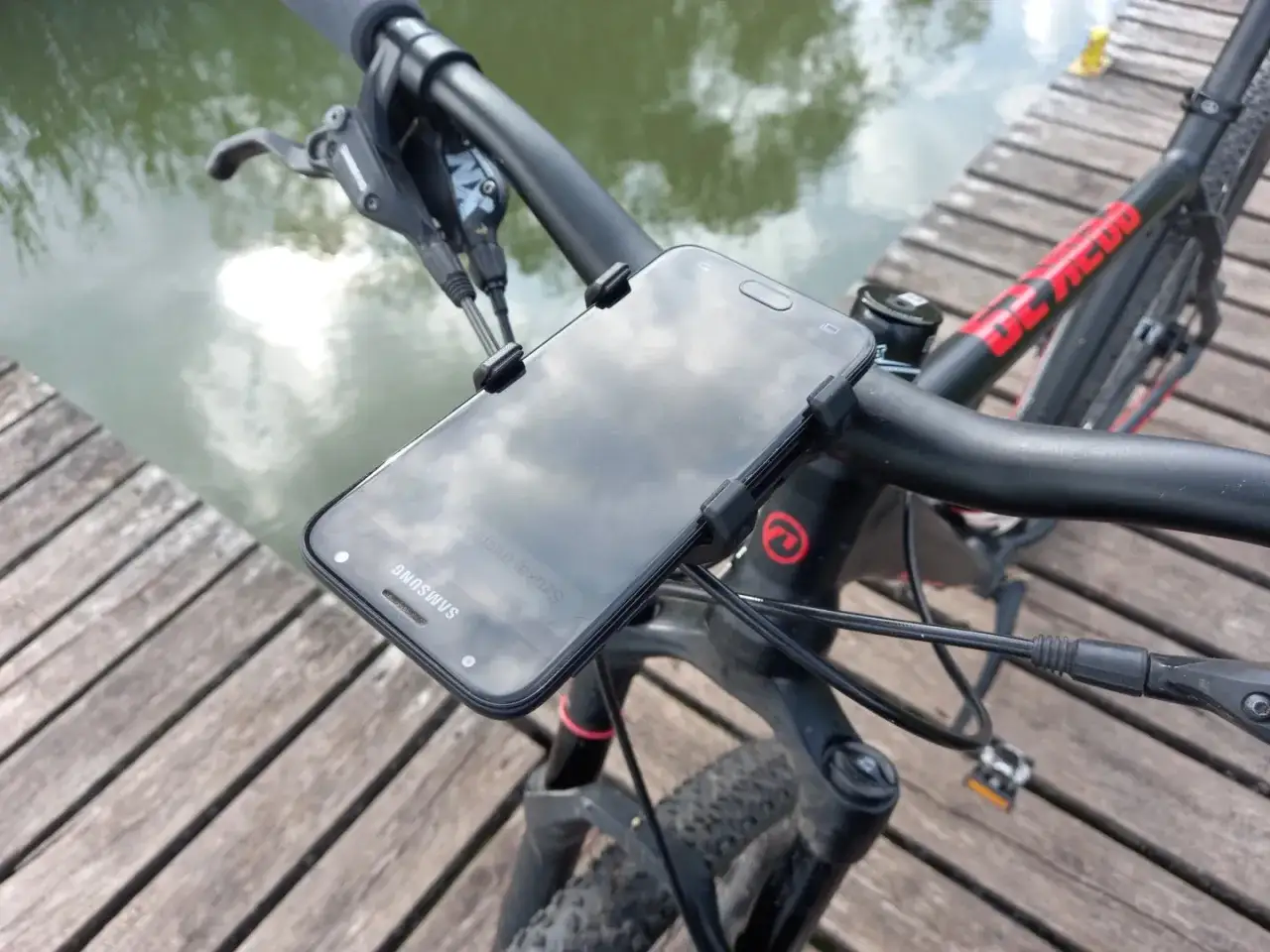 Solidny uchwyt na telefon do roweru, idealny do nawigacji podczas jazdy. Telefon Samsung zamocowany na kierownicy.