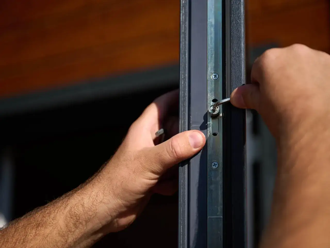 Dłoń z kluczem imbusowym reguluje okno, przygotowując je do zimy. Prosty sposób, jak wyregulować okna na zimę.