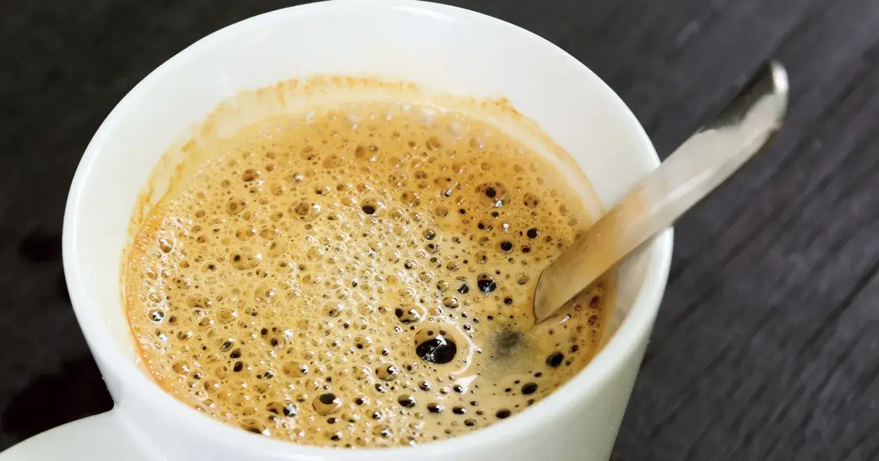 Puszysta pianka na kawie w białej filiżance. Czy kawa jest lekkostrawna? Zależy od sposobu parzenia i dodatk&oacute;w.