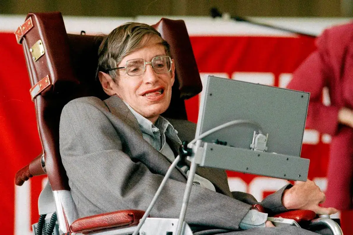Stephen Hawking, wybitny naukowiec na wózku, w garniturze, przed komputerem.