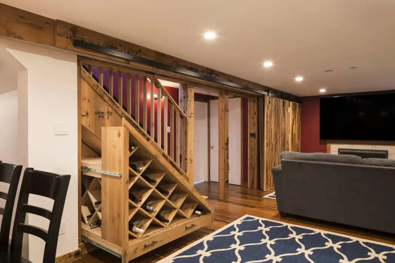 Drewniana piwnica z winiarnią pod schodami i drzwiami przesuwnymi. Inspiracje dla miłośników wina.