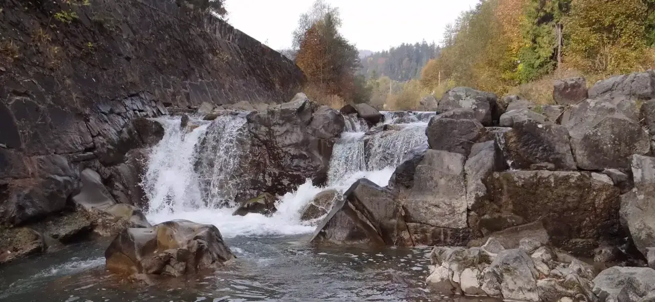 Wodospad szepcze na potoku Hylaty, otoczony kamieniami i jesiennymi drzewami.
