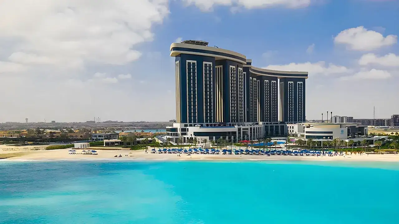 Luksusowy Rixos Premium Alamein z widokiem na turkusowe morze i piaszczystą plażę.