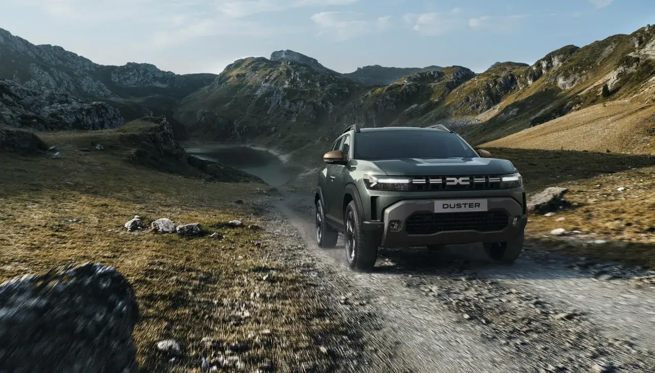 Zielony Dacia Duster off road pokonuje kamienistą drogę w górskim krajobrazie.