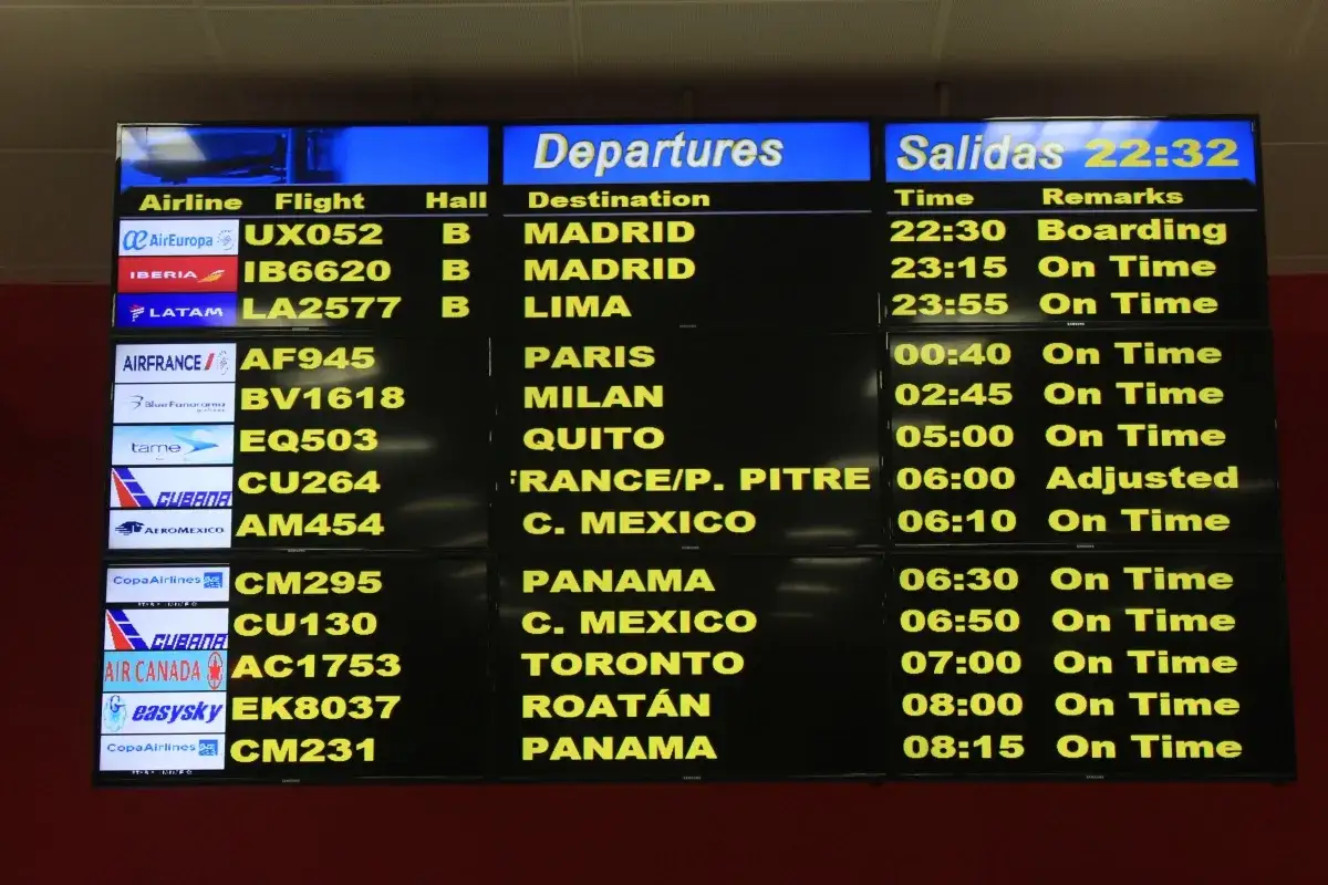 hala odlotów na lotnisku z pasażerami i tablicą odlotów