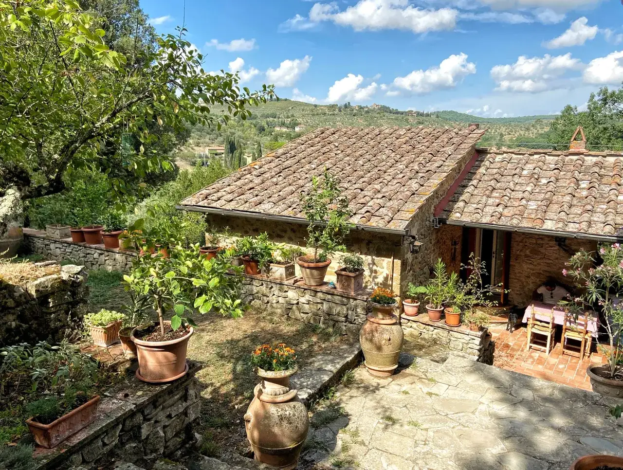 Kamienne domy, tarasy z donicami i widok na wzg&oacute;rza Toskanii. Idealne miejsce, gdzie szukać nocleg&oacute;w we Włoszech.