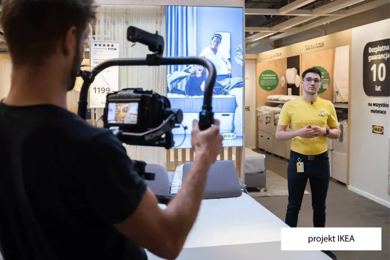 Operator kamery filmuje pracownika IKEA, który opowiada o materacach. Tak właśnie producenci na planie filmowym tworzą materiały promocyjne.