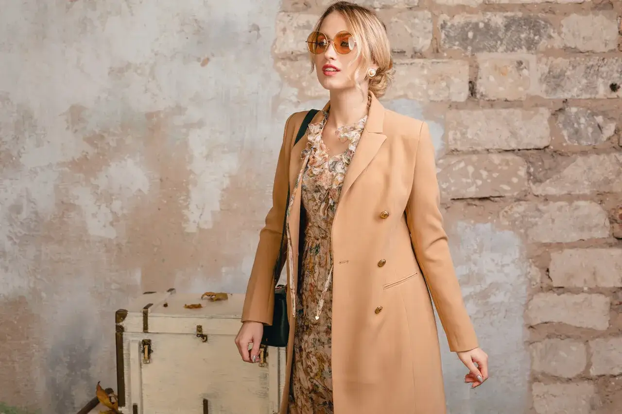 Elegancka kobieta w płaszczu w kolorze camel, który pasuje do jej karnacji i podkreśla stylizację.