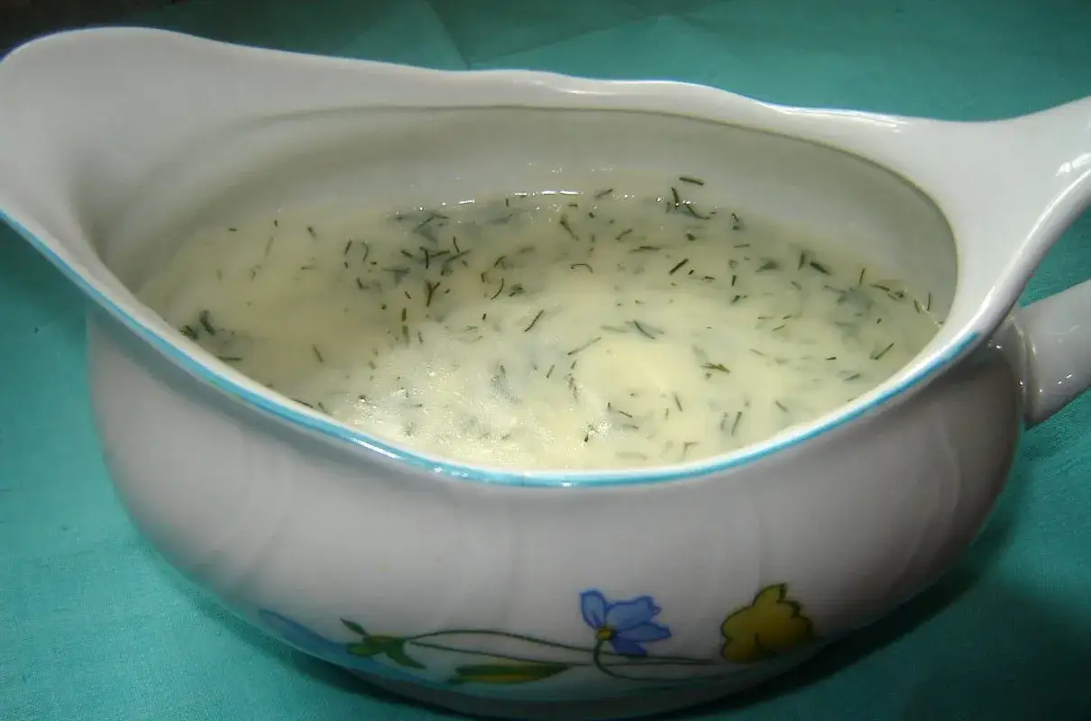 Kremowy sos koperkowy w sosjerce z błękitnym rantem i kwiatowym wzorem. Idealny do ryby lub ziemniaków.