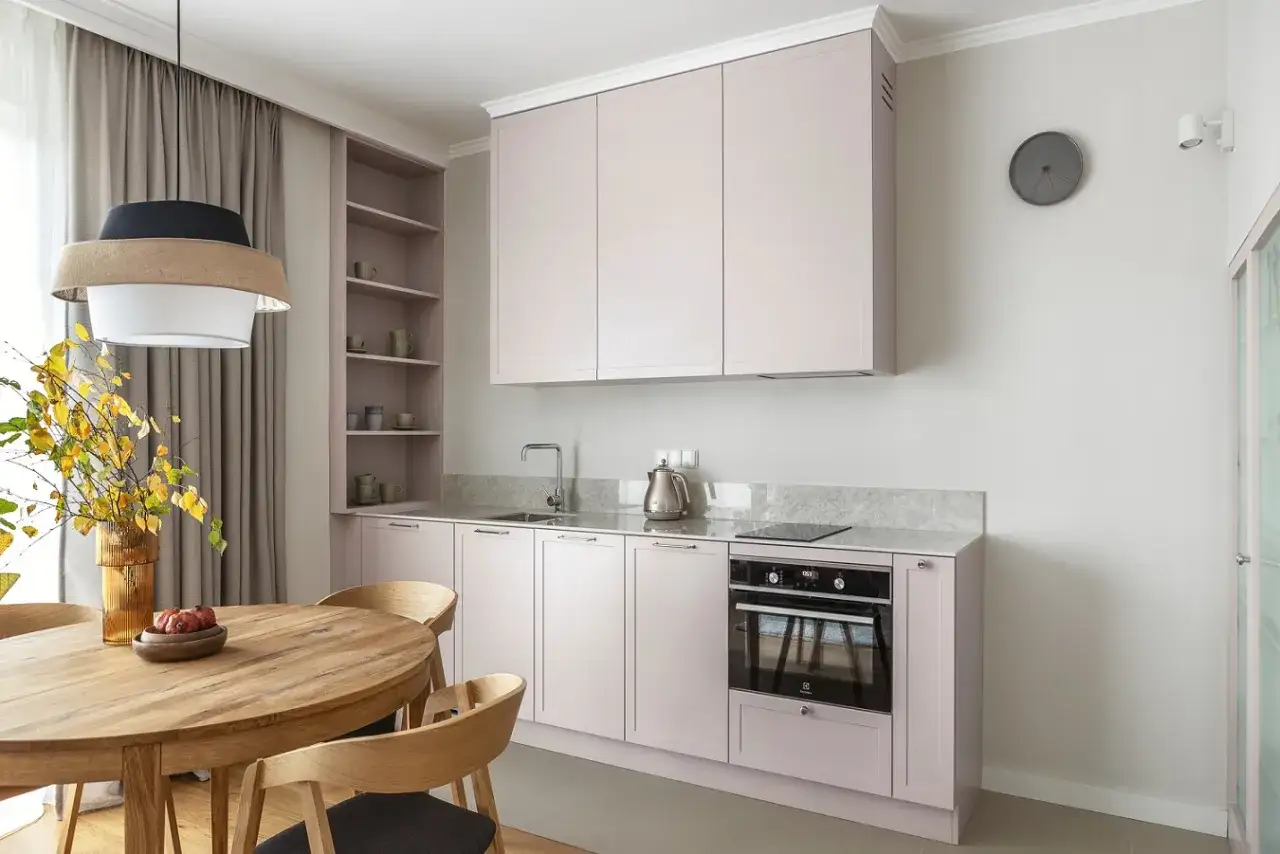 Nowoczesna kuchnia z jasnor&oacute;żowymi frontami, gdzie blat kuchenny na ścianie zamiast płytek tworzy sp&oacute;jną całość.