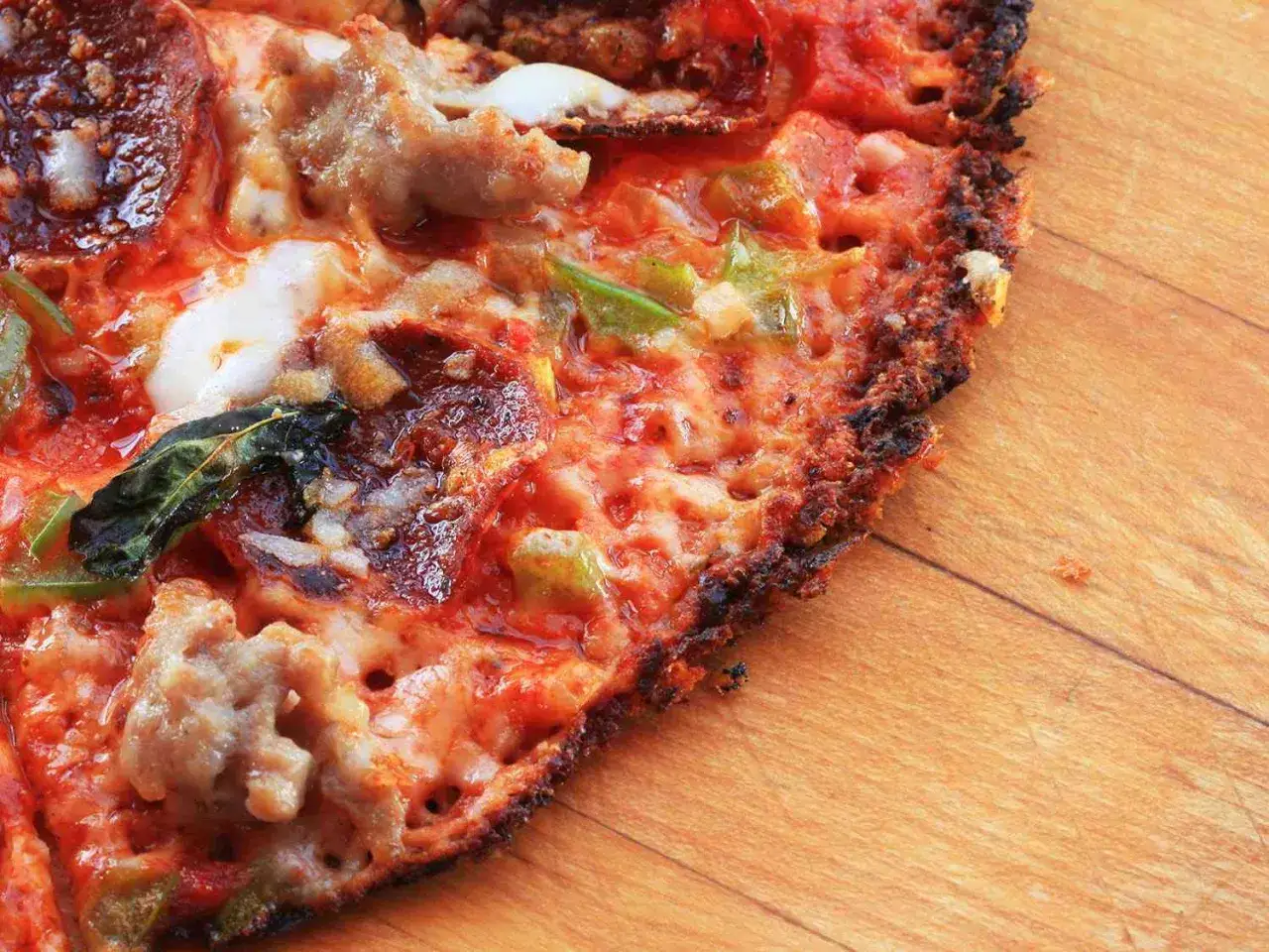 Chrupiąca pizza z tortilli z serem, kiełbasą i papryką, apetycznie przyrumieniona na drewnianym blacie.