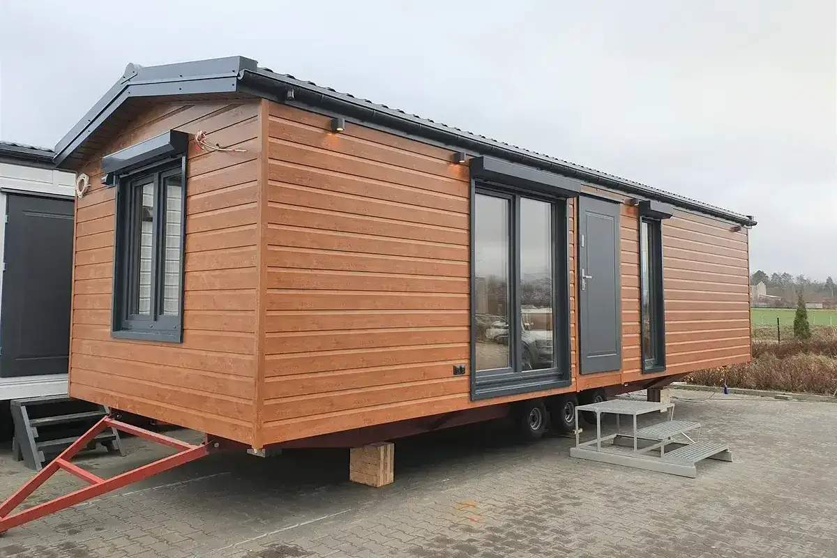 Nowoczesny domek letniskowy na zgłoszenie, z drewnianą elewacją i dużymi oknami, gotowy do transportu.