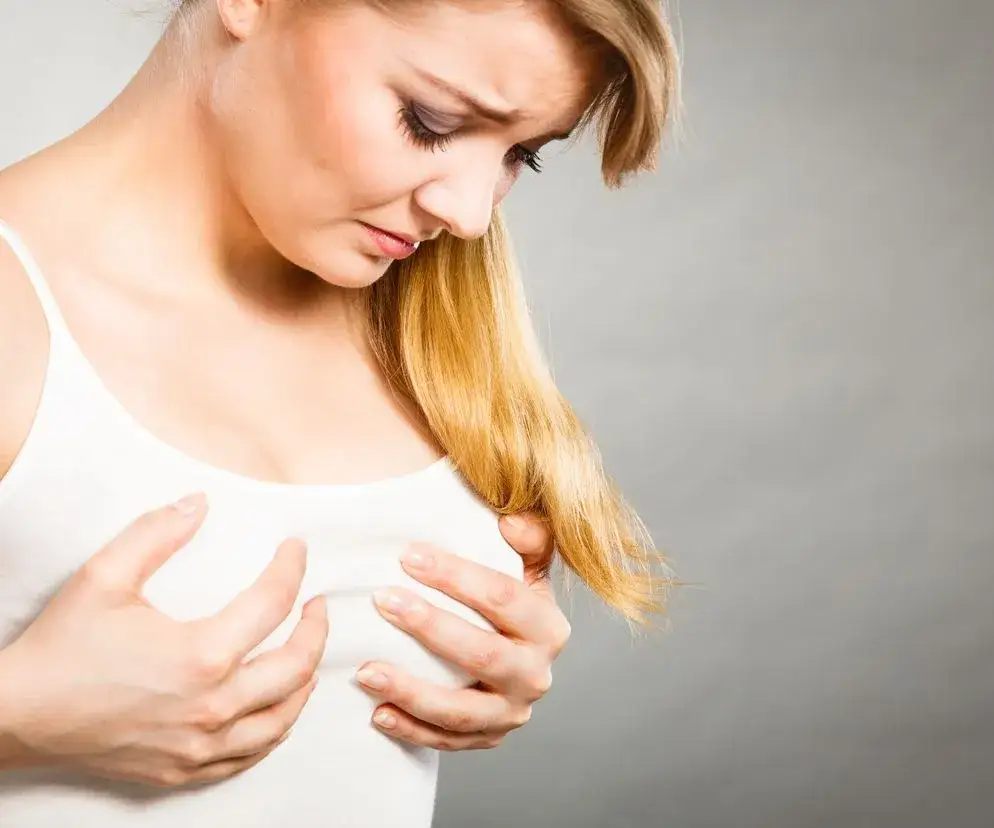 kobieta zmartwiona b&oacute;lem piersi, kobieta dotykająca piersi, kobieta myśląca o zdrowiu